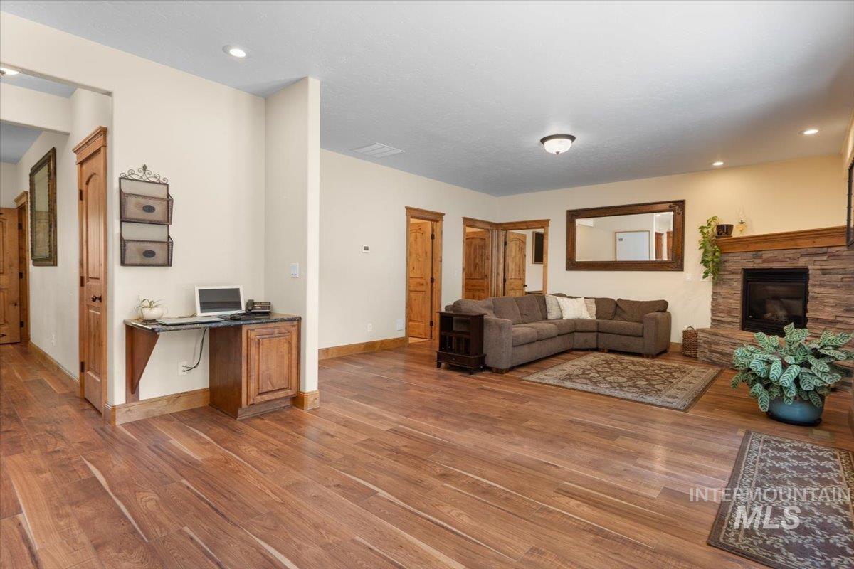 4154 North Tipton Avenue Meridian, ID 83646 - Photo 10 of 50 Spacious living area featuring wood-finish flooring, recessed lighting, and a stone-faced fireplace with a wood mantel