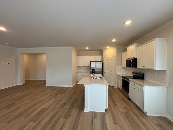 a large kitchen with kitchen island a sink dishwasher a stove and a refrigerator with wooden floor