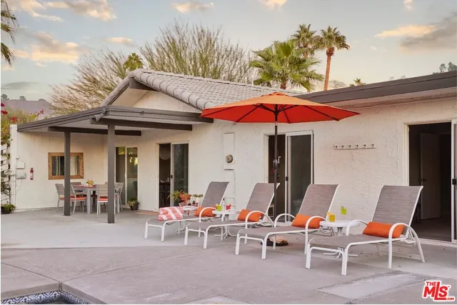 a view of a patio with a table and chairs under an umbrella