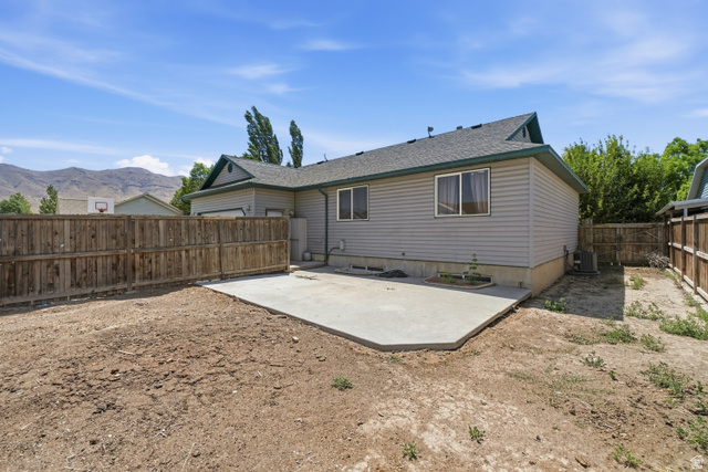 2135 East White Pine Road Eagle Mountain, UT 84005 - Photo 21 of 23 Rear exterior of a single-story residence featuring light gray siding and a dark shingle roof