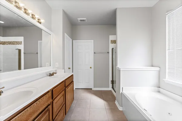 a spacious bathroom with a tub sink and mirror