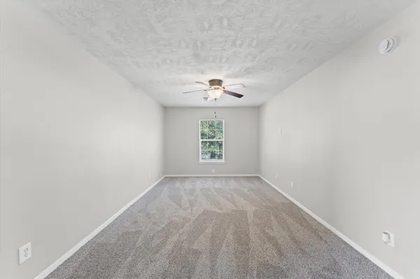 an empty room with a window and a ceiling fan