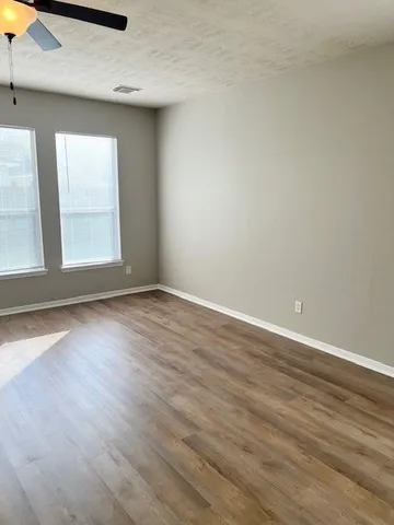 an empty room with wooden floor and windows
