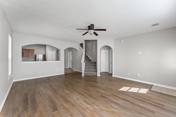 a view of empty room with wooden floor and ceiling fan
