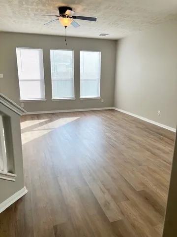 an empty room with wooden floor and windows