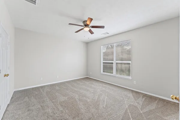 an empty room with windows and fan