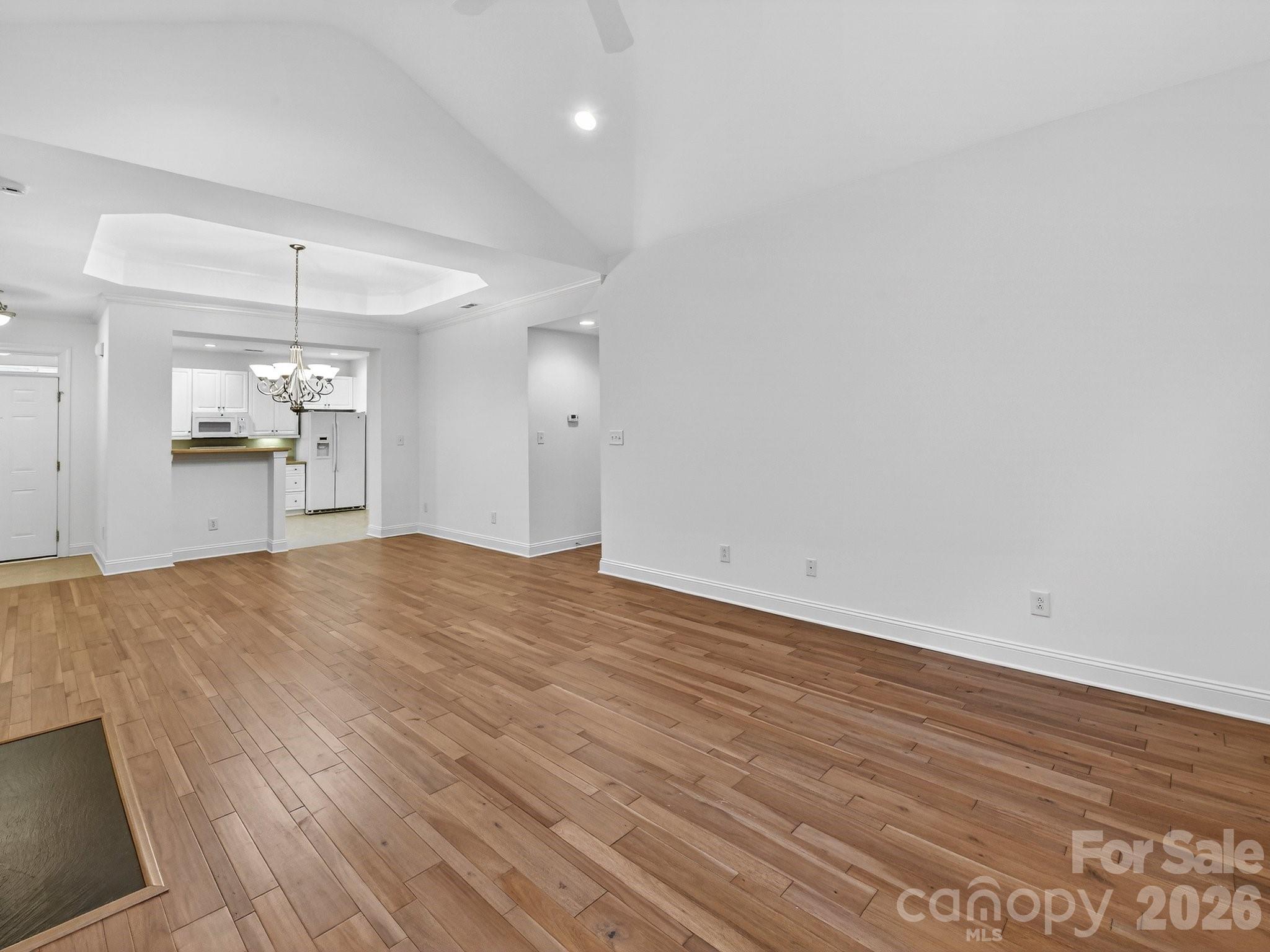 2963 Bellasera Way Matthews, NC 28105 - Photo 11 of 45 an empty room with wooden floor and kitchen view