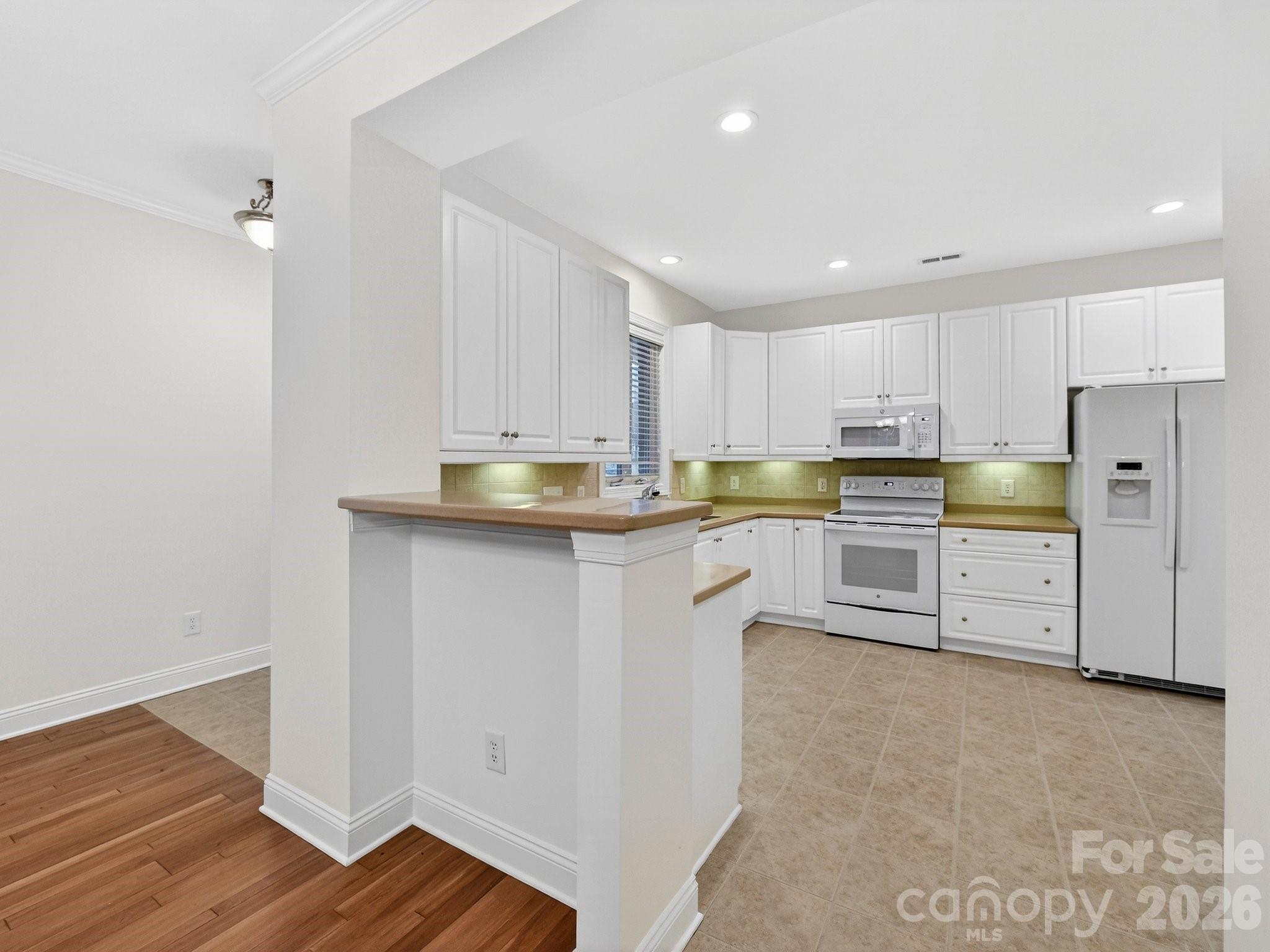 2963 Bellasera Way Matthews, NC 28105 - Photo 13 of 45 a kitchen with stainless steel appliances white cabinets and wooden floors