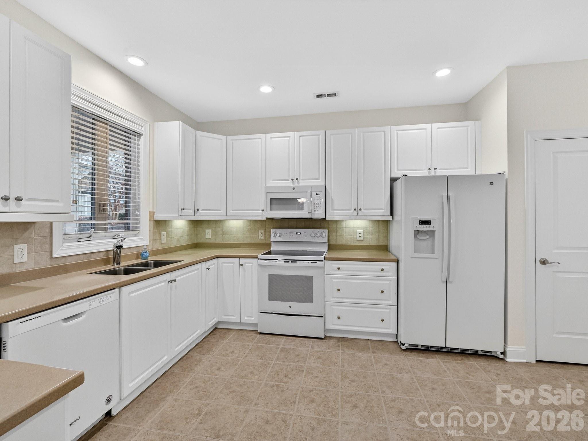 2963 Bellasera Way Matthews, NC 28105 - Photo 14 of 45 a kitchen with granite countertop white cabinets and white stainless steel appliances