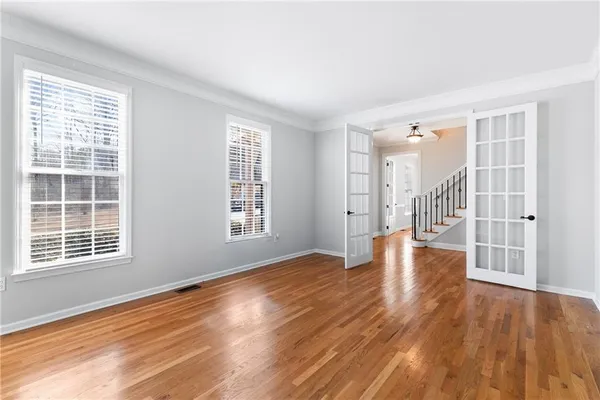 an empty room with wooden floor and windows