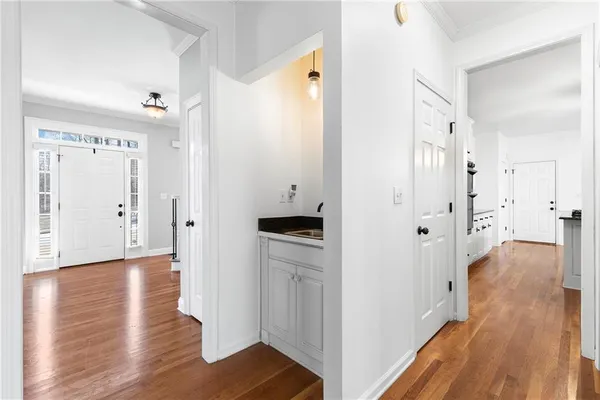 a view of a hallway with wooden floor and a bathroom