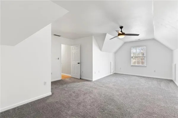 an empty room with windows and ceiling fan
