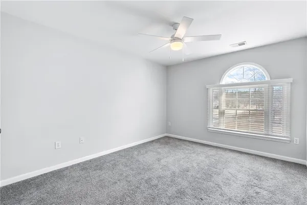 an empty room with chandelier fan and windows