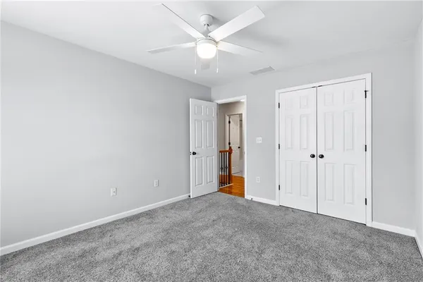 an empty room with closet and a ceiling fan