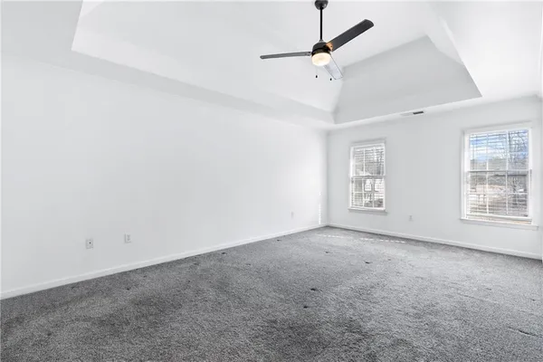 an empty room with windows and fan