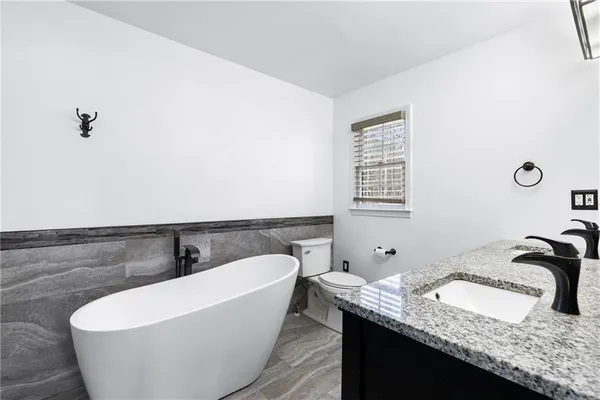a bathroom with a granite countertop sink and a bathtub