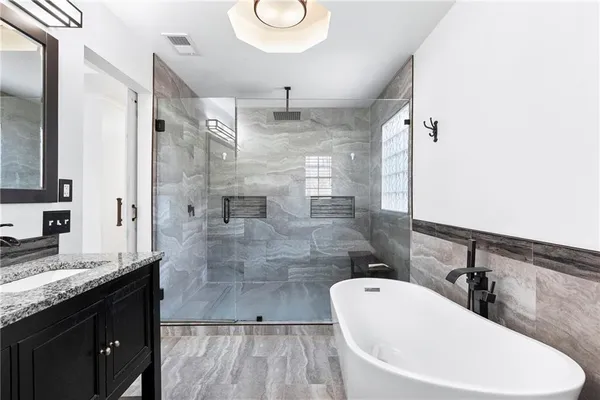 a bathroom with a granite countertop bathtub sink vanity granite and shower
