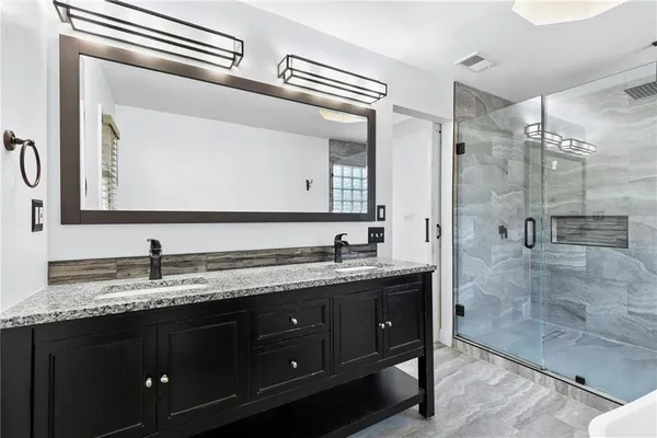 a bathroom with a granite countertop sink a mirror and shower