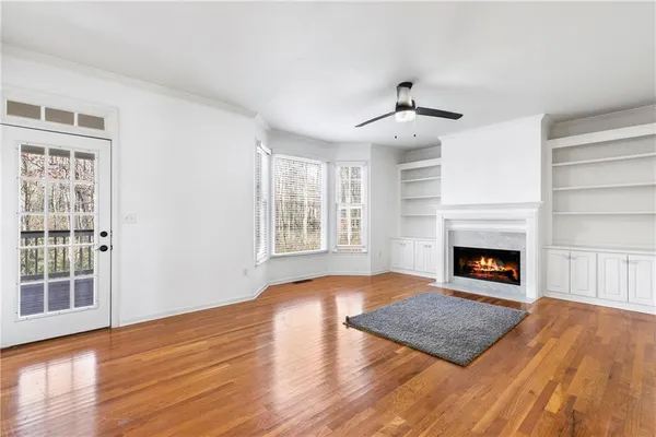 a view of an empty room with wooden floor fireplace and a window