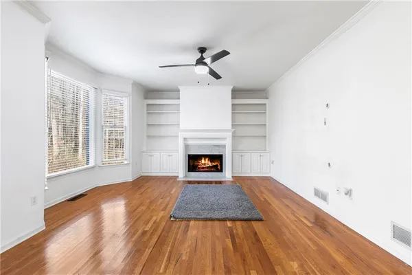 an empty room with windows fireplace and wooden floor