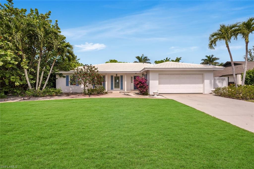 4711 Crayton Road Naples, FL 34103 - Photo 1 of 14 a view of a house with a big yard and palm trees