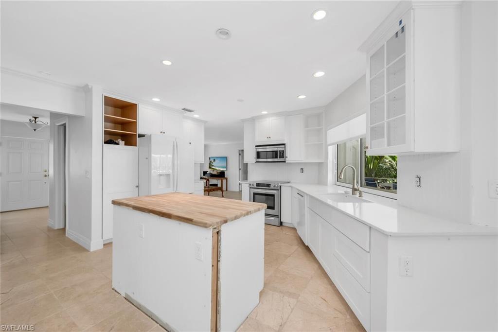 4711 Crayton Road Naples, FL 34103 - Photo 9 of 14 a large kitchen with stainless steel appliances kitchen island granite countertop a refrigerator and a stove top oven