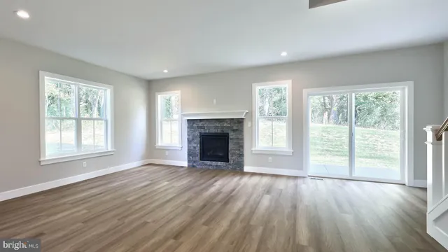 an empty room with wooden floor fireplace and windows