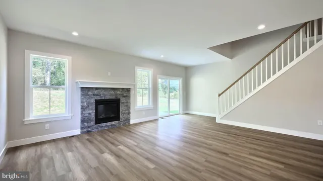 a view of an empty room with wooden floor fireplace and a window