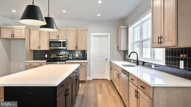 a large kitchen with stainless steel appliances granite countertop a sink a stove and a refrigerator