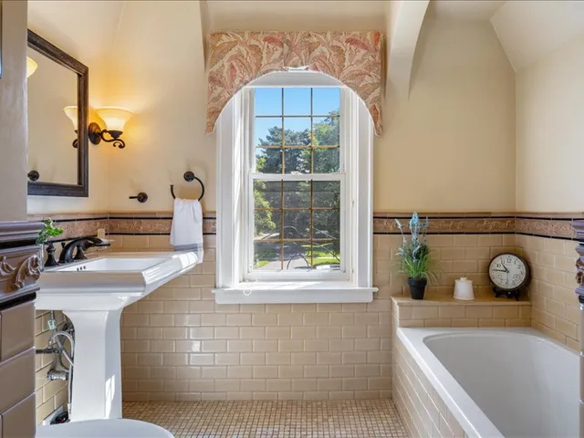 a bathroom with a tub a sink and a large mirror