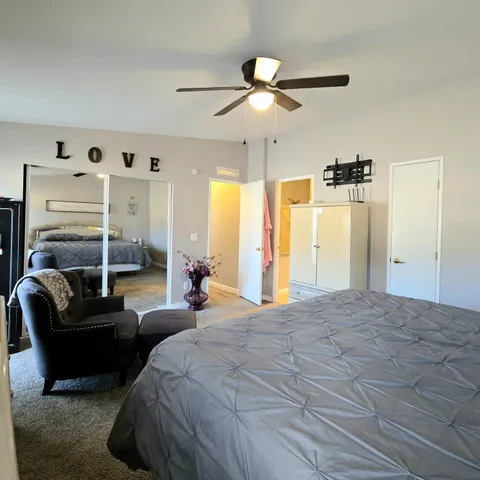 a spacious bedroom with a bed a couch and a ceiling fan