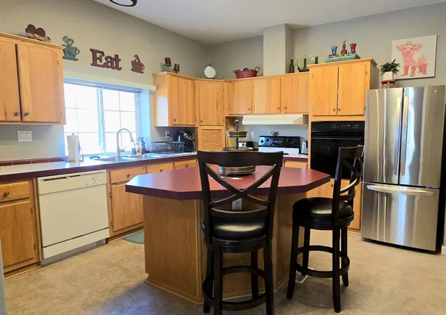 a kitchen with stainless steel appliances granite countertop a table chairs and a refrigerator