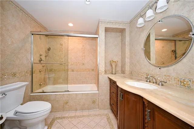 a bathroom with a bathtub shower sink mirror vanity and a toilet