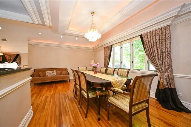 a dining room with wooden floor a chandelier a wooden table and chairs