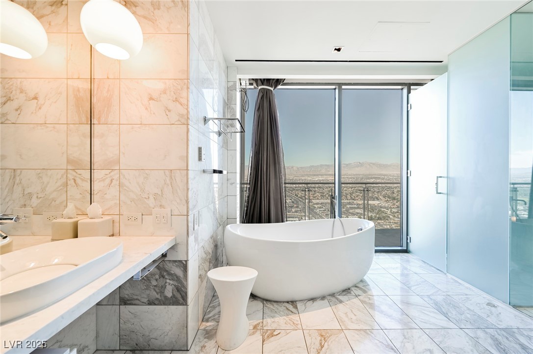 4381 West Flamingo Road, Unit 5708 Las Vegas, NV 89103 - Photo 18 of 34 Full bathroom featuring a healthy amount of sunlight, a freestanding tub, expansive windows, and marble finish floor