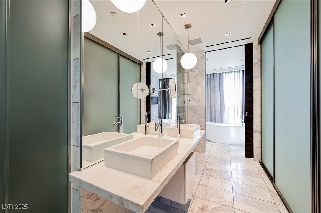 4381 West Flamingo Road, Unit 5708 Las Vegas, NV 89103 - Photo 20 of 34 Full bathroom featuring a healthy amount of sunlight, a freestanding tub, expansive windows, and marble finish floor