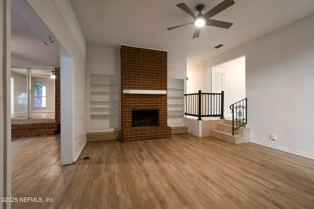 a view of a livingroom with wooden floor and a ceiling fan