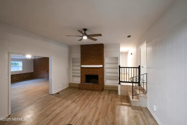 a view of a livingroom with wooden floor and a fireplace