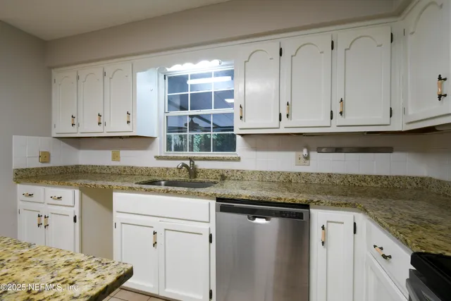 a kitchen with granite countertop white cabinets and sink