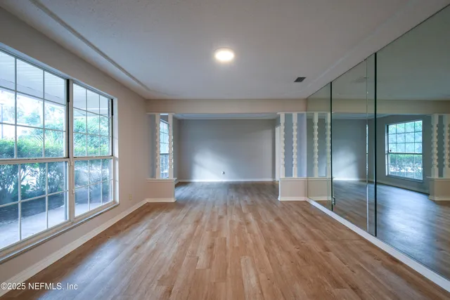 a view of empty room with wooden floor and fan