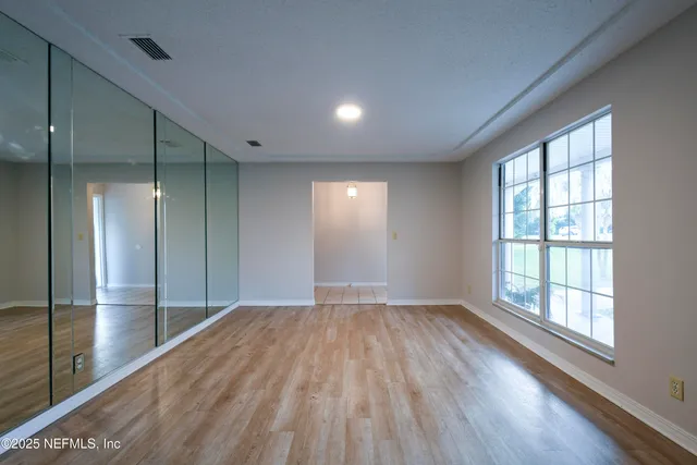 a view of empty room with wooden floor and fan