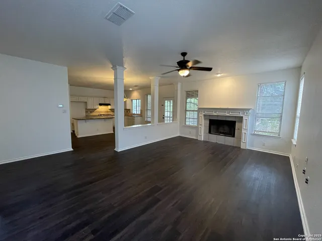 an empty room with wooden floor a fireplace and a window