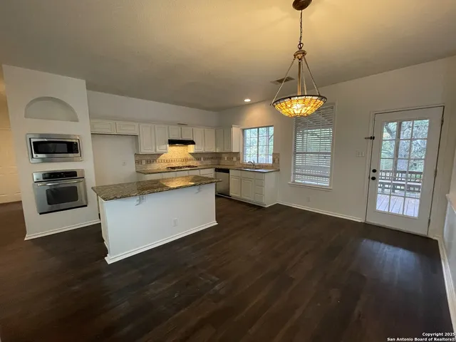a kitchen with stainless steel appliances granite countertop a stove a refrigerator and a fireplace with wooden floor