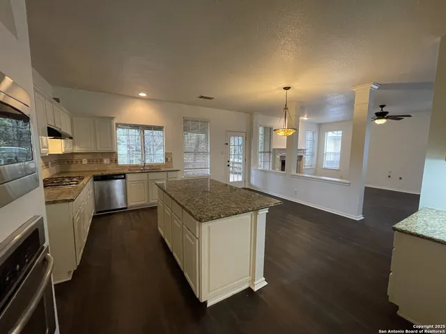 a kitchen with granite countertop a sink a counter top space stainless steel appliances and cabinets