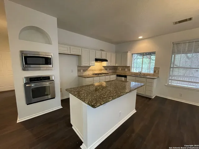 a kitchen with stainless steel appliances granite countertop a stove a sink and a refrigerator
