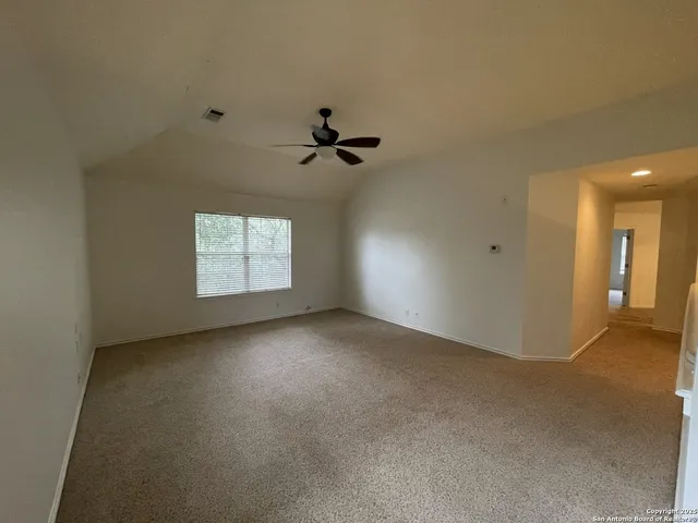 an empty room with windows and ceiling fan