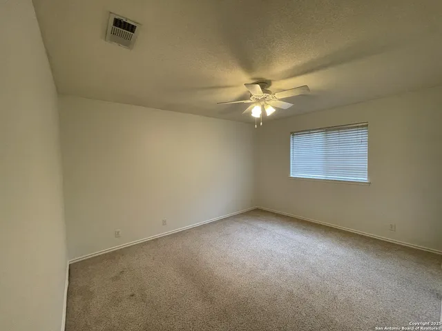 an empty room with a chandelier fan and windows