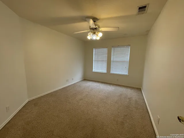 an empty room with a window and a ceiling fan