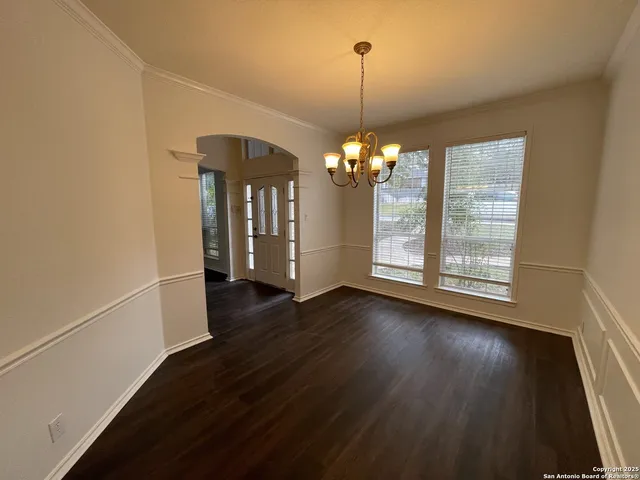 a view of a room with wooden floor chandelier and a window