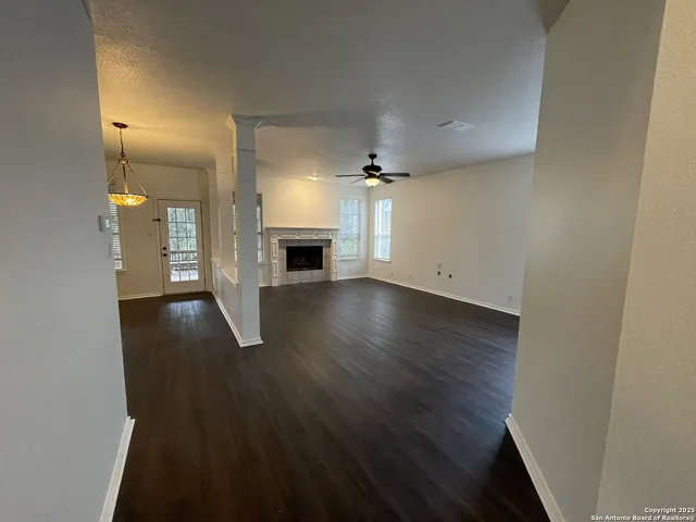 an empty room with wooden floor a fireplace and windows